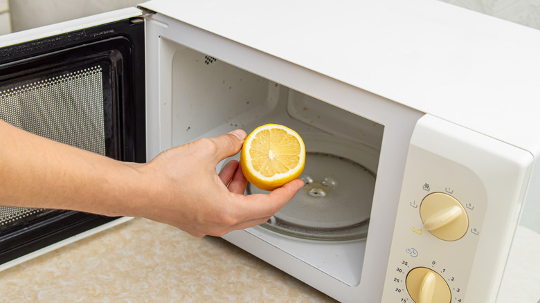 Person placing lemon in microwave