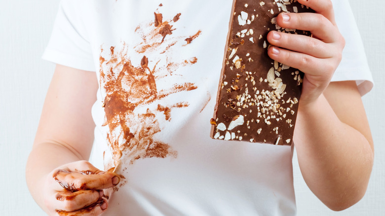 child holding chocolate bar with chocolate smeared on white shirt