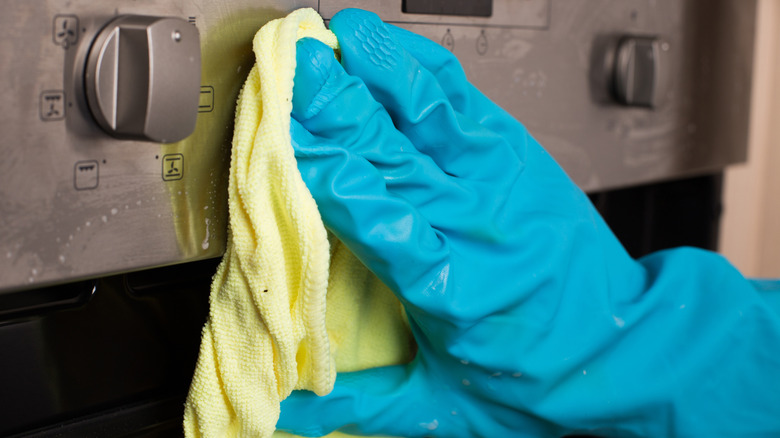 A close-up shot of someone using a microfiber cloth to clean stove knobs