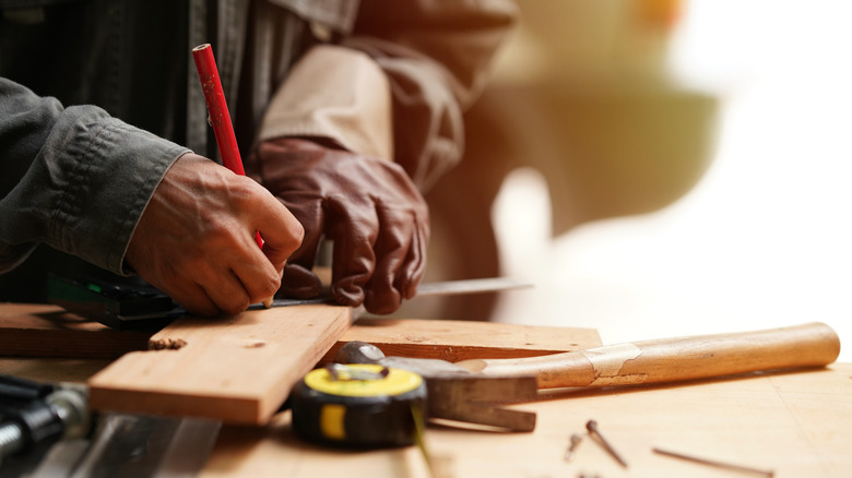 Close-up shot of a person making markings on a wood plank
