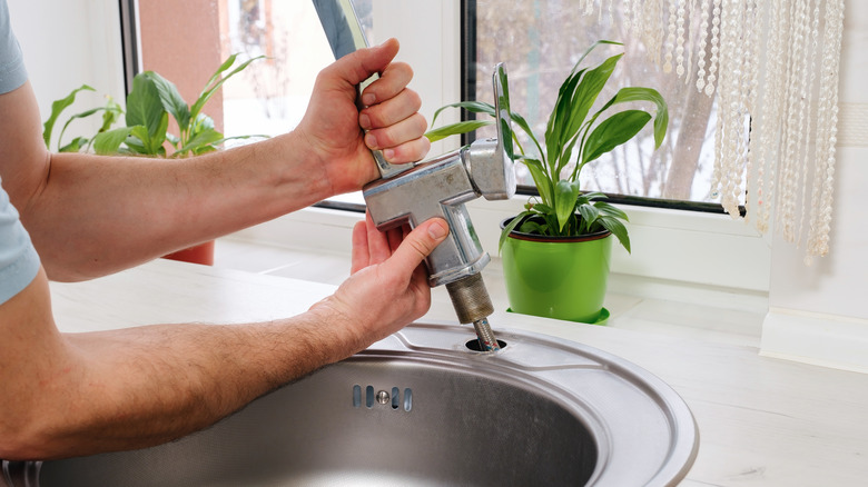 Plumber removing kitchen faucet