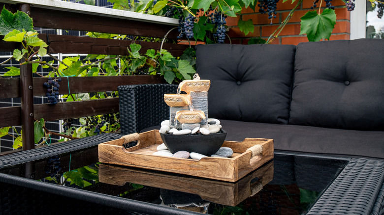 Balcony with zen fountain on a dark coffee table and a dark sofa in the background