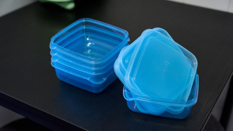 A stack of blue plastic containers and lids sitting on a black square table