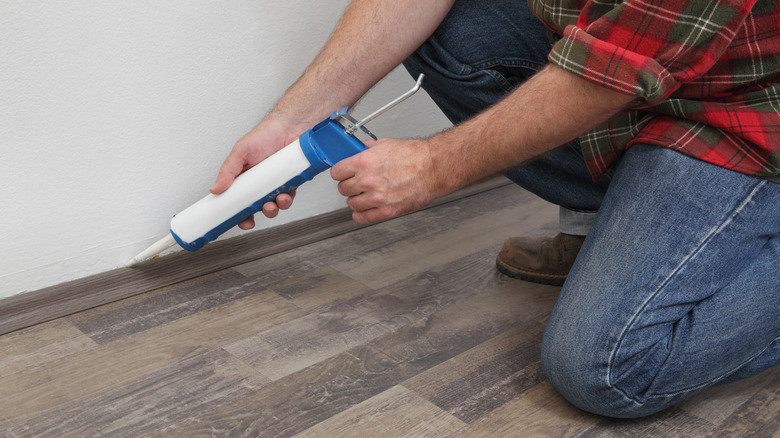 Person using manual caulk gun