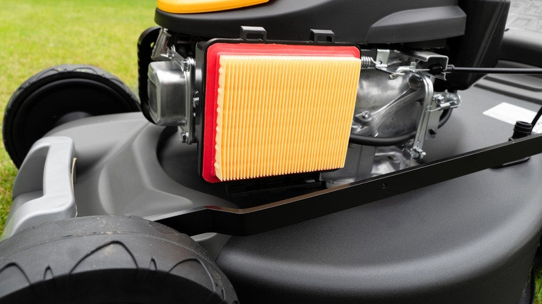 A new yellow and red air filter installed in a lawn mower.