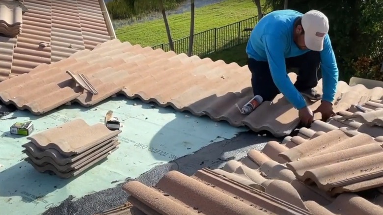 A man removing damaged tiles from a roof