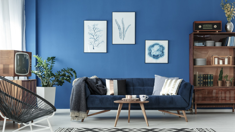 Blue lounge with blue sofa, patterned carpet, wooden cabinets, and vintage design elements.