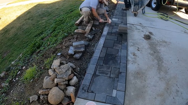 Person installing pavers on driveway extension