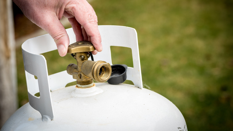 Person turning knob propane tank