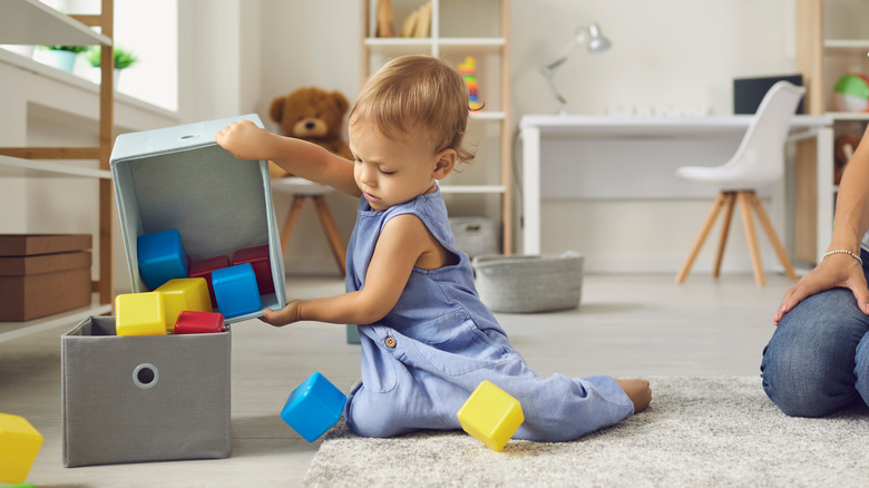 child placing toys in box