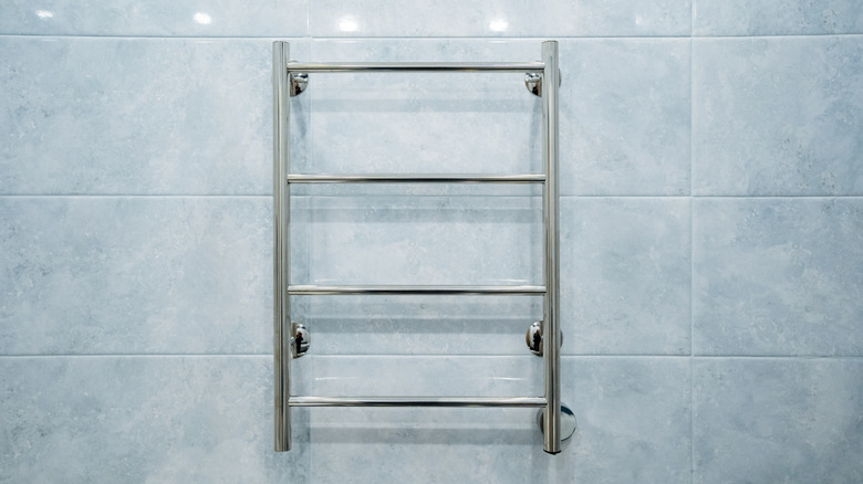 stainless steel towel rack on a blue tile wall
