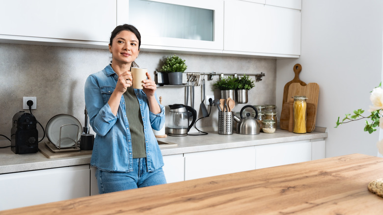 woman standing in kitchen with cluttered countertops