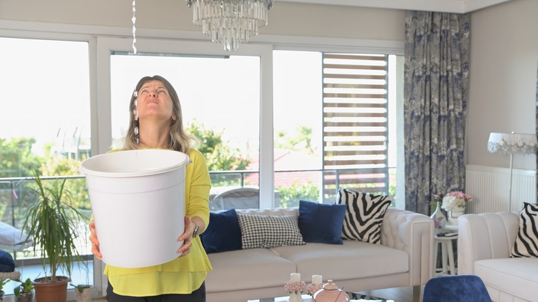 Woman catching leak in bucket