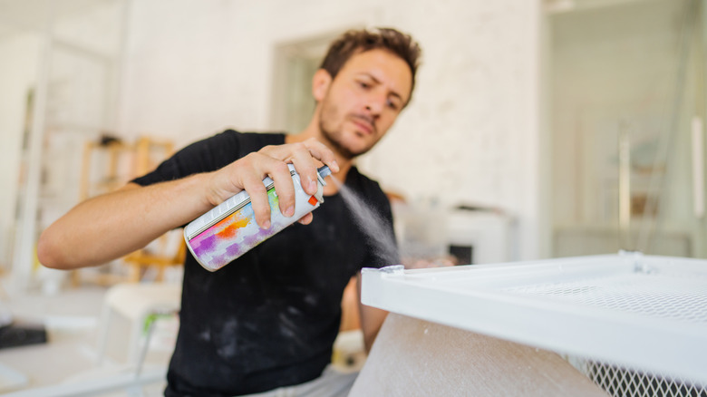 man spray painting a vent 