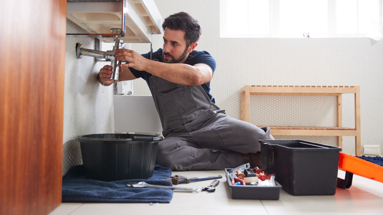 Man fixing pipe under sink