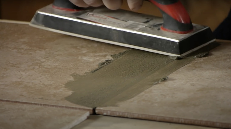 person adding grout to tiles