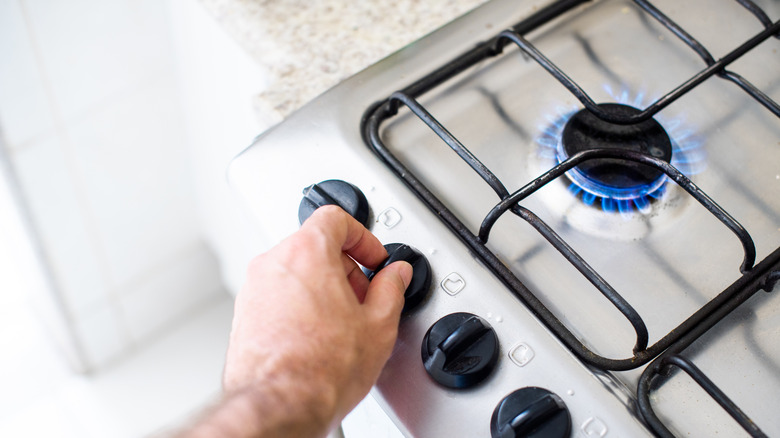 A person turning on a burner on a white gas stove