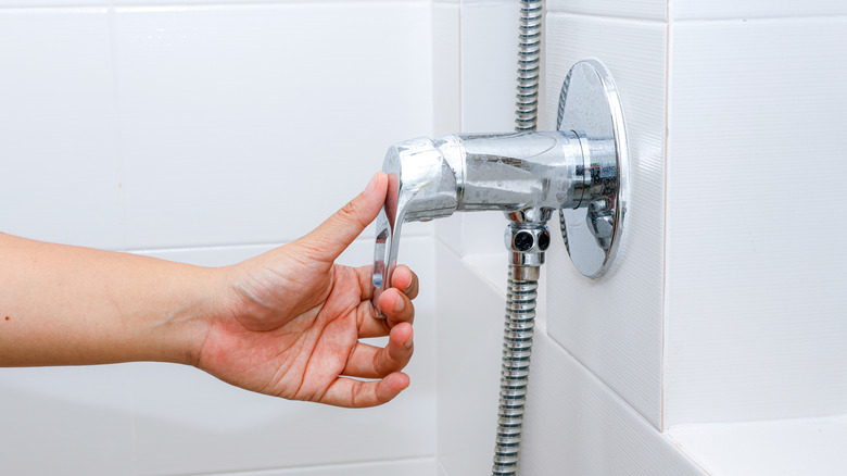 A hand adjusting the shower valve