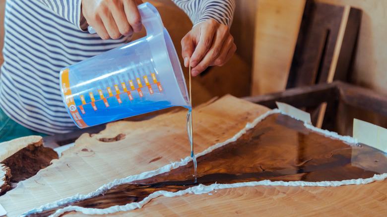 A person filling in wood gaps with epoxy resin.