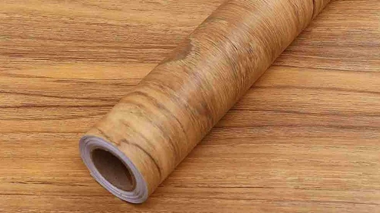 A roll of wood finish peel-and-stick wallpaper.
