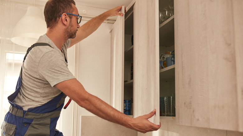 A person fixing kitchen cabinet door.