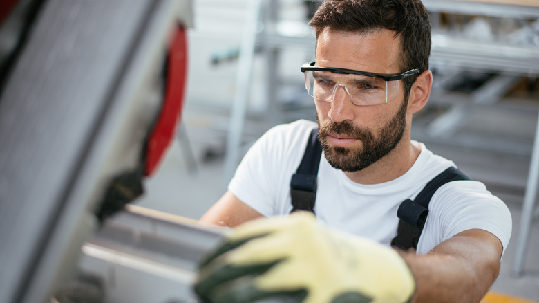 A man working with safety glasses and heavy duty gloves