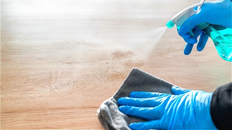 Gloved hands cleaning wood surface