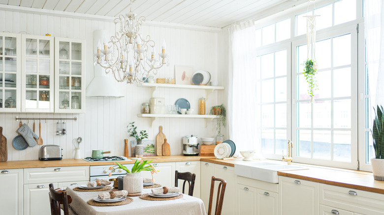 All-white minimal farmhouse kitchen with open shelves and glass-front cabinets