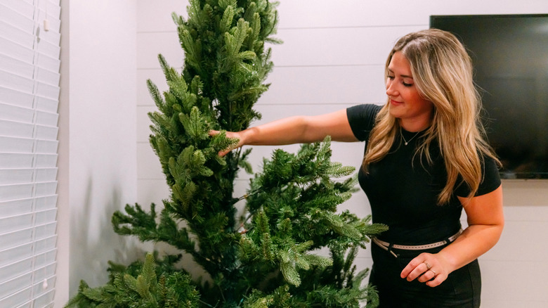 A woman setting up her artificial Christmas tree.