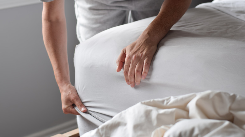 man changing fitted sheet
