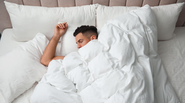Man sleeping under white comforter