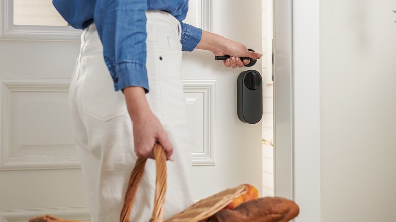 Person opening smart lock door while holding a basket of bread