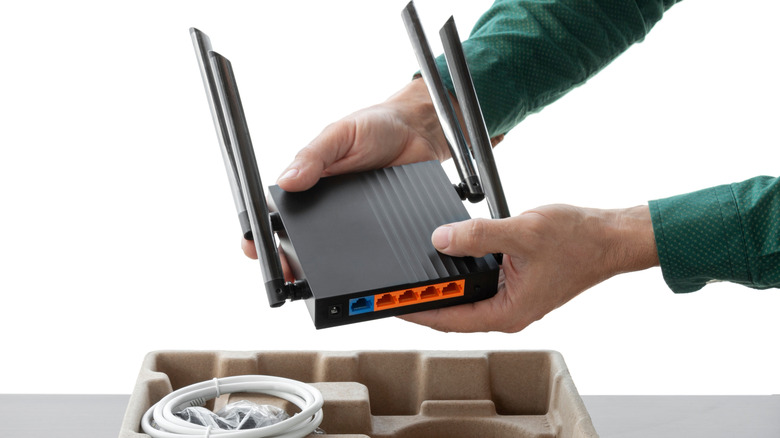 Person removing a Wi-Fi router from its carton container