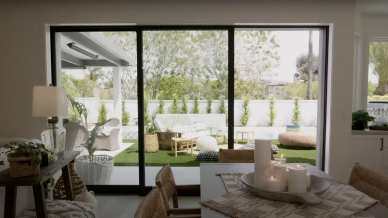A custom glass exterior door reveals a large patio surrounded by tropical plants