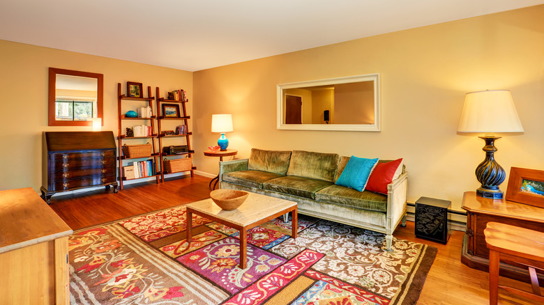 a living room with wood furniture and a colorful rug in front of the sofa