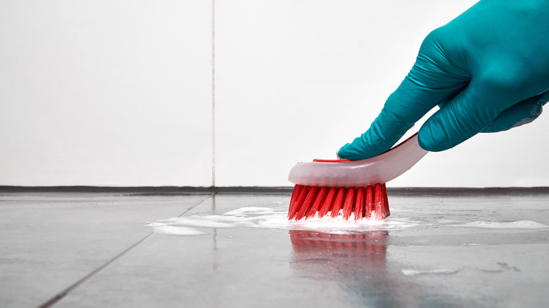 Someone scrubbing floor with toothbrush