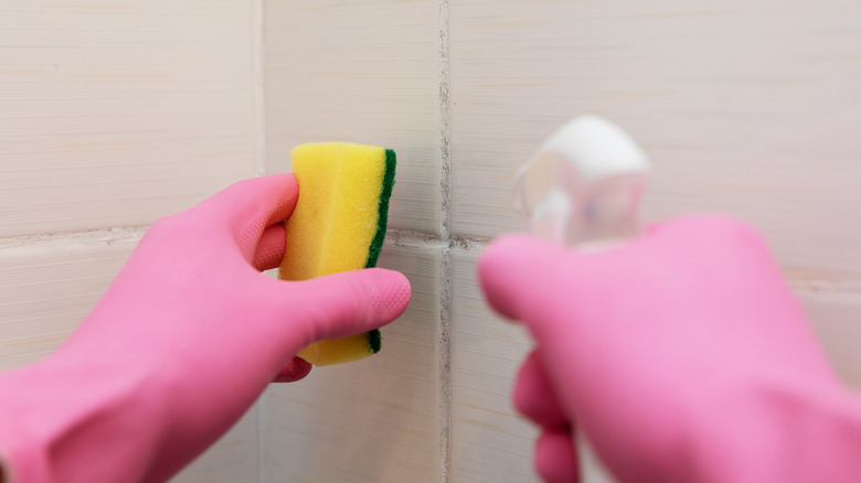 person cleaning shower grout