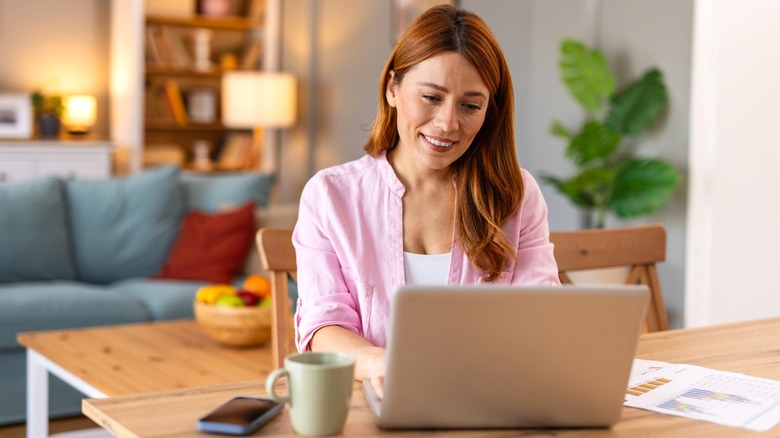 Smiling woman working on laptop at kitchen table