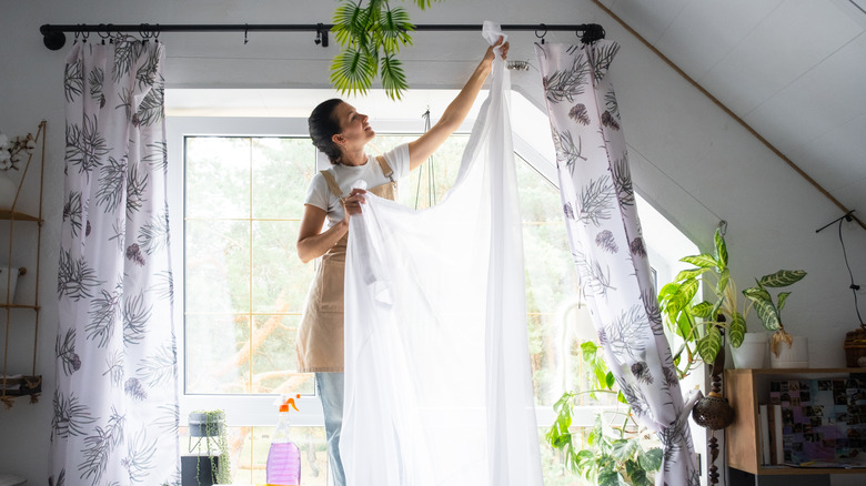 A woman hanging up curtains