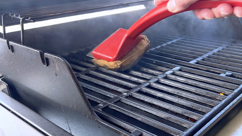 A man cleaning a grill with a brush designed for the purpose