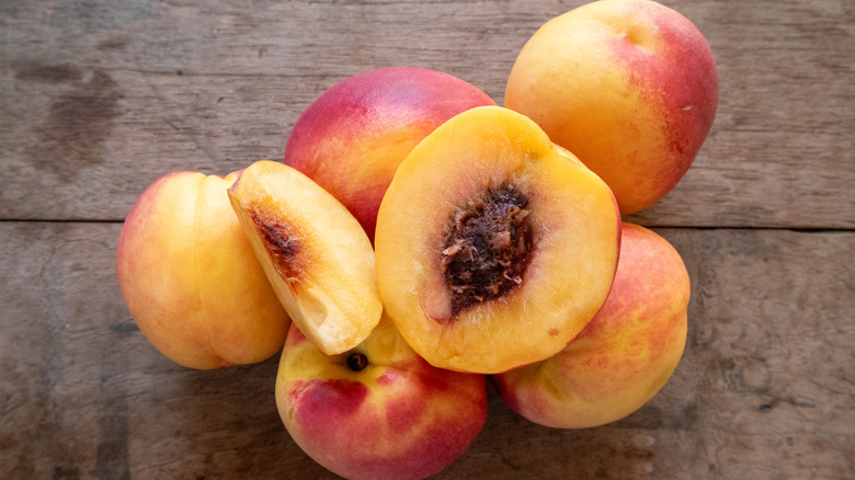 A group of ripe peaches with the pit exposed.