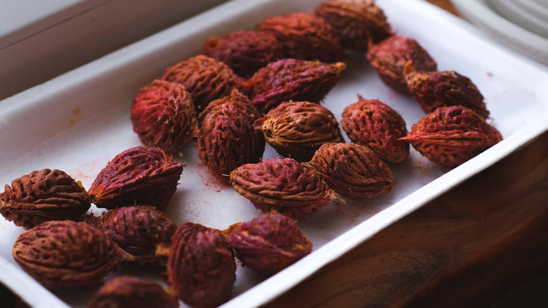 Cleaned peach pits sitting in a white plastic tray on a windowsill.