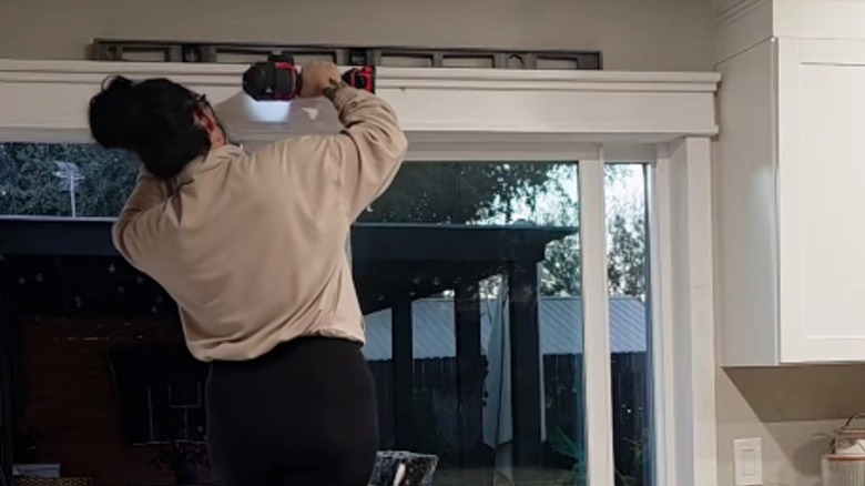 A woman using a drill to install a sliding door trim
