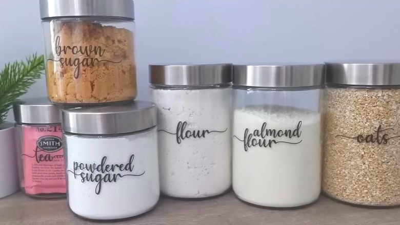 Glass jars containing various kitchen staples rests on a countertop.