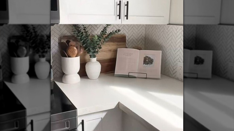 A cookbook rests on a display easel on a kitchen countertop.