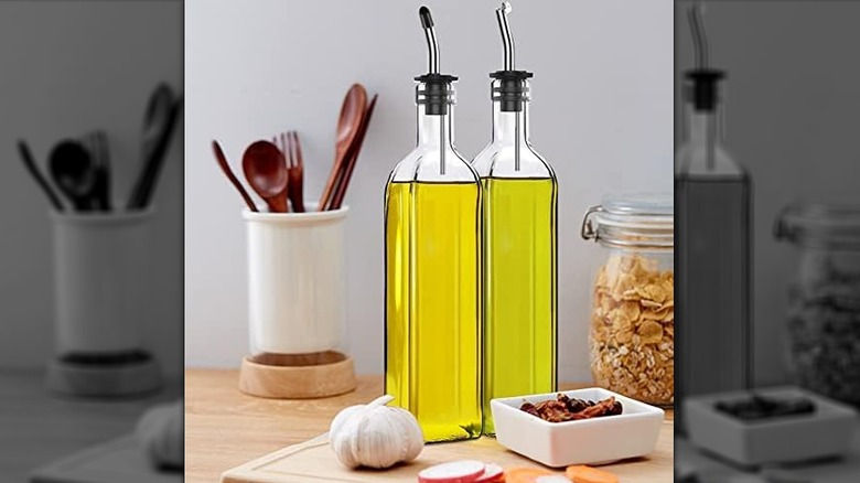 Oil bottles rest on a cutting board in a kitchen countertop.