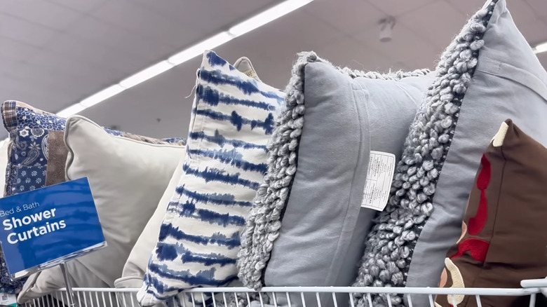 Rack of throw pillows at a thrift store in various colors, patterns, and materials