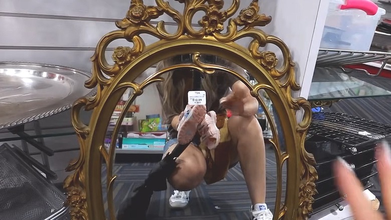 Person in a thrift store looking at an ornately framed mirror