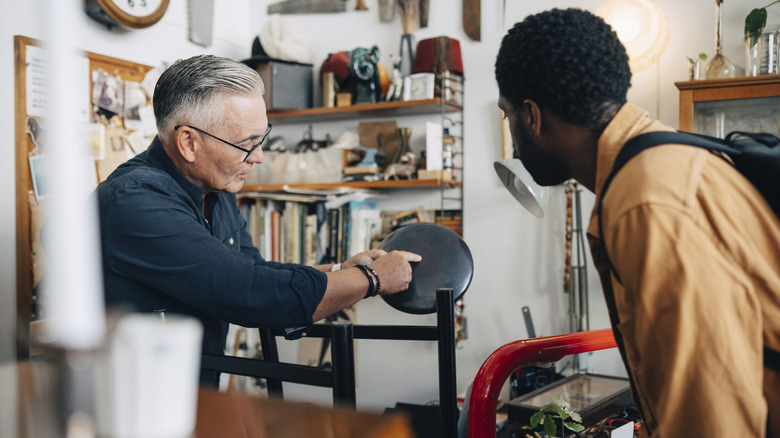 Man showing other man an antique item in a thrift store
