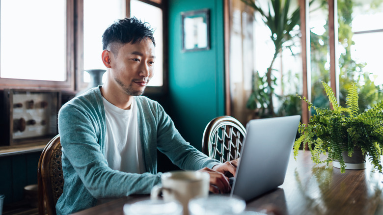 Man using laptop in home with plants and vintage decor